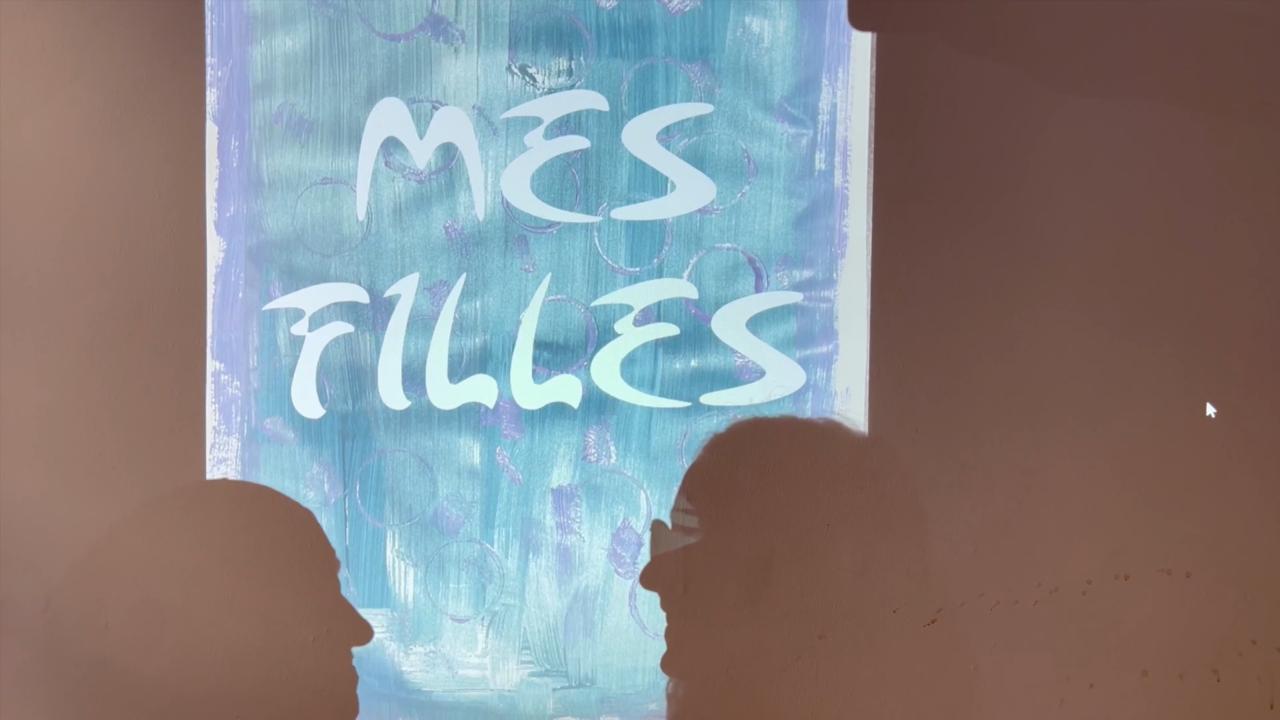 Ombre de deux femmes devant une peinture où il est écrit "Mes filles"